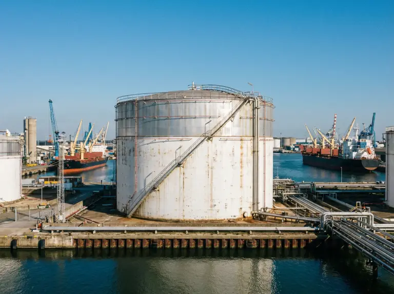 Crude storage facility with large tanks and pipework next to a working port
